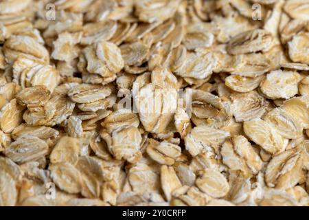 Versò una grande quantità di fiocchi di avena primo piano, sfondo di farina d'avena cruda cruda Foto Stock