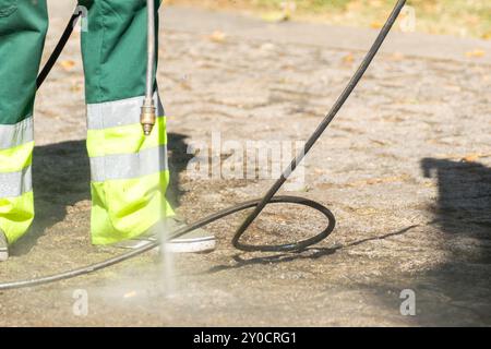 obiettivo selettivo, un addetto alle pulizie pubblico che pulisce la strada con acqua in pressione Foto Stock