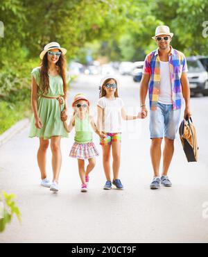 Felice famiglia giovane a piedi con la chitarra di spesa ora spensierata insieme. I viaggi e le vacanze concept Foto Stock