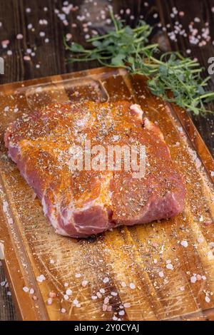 Pezzi di carne di maiale marinati con spezie e sale, collo di maiale preparato per la cottura con spezie miste con sale marino Foto Stock