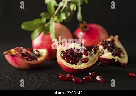 Primo piano di maturi frutti di melograno e i semi di più di una texture di sfondo nero Foto Stock