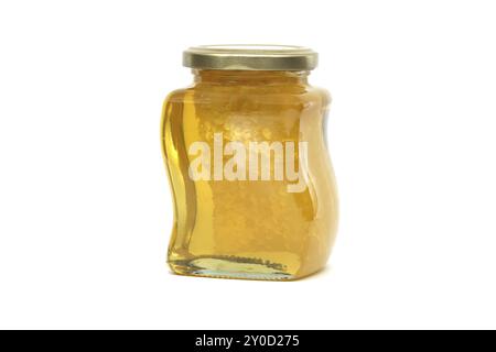 Un vaso di vetro con coperchio dorato contiene miele con favo riempito quasi fino in cima, su sfondo bianco Foto Stock