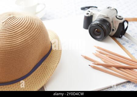 Matita a colori, bozzetto, caffè e macchina fotografica posizionati sulla scrivania Foto Stock