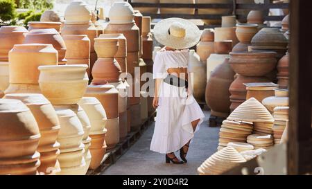 La giovane donna si nasconde dietro il cappello in un cortile di ceramica, incarnando mistero ed eleganza del patrimonio spagnolo mentre l'estate svanisce in autunno. Concetto di Foto Stock