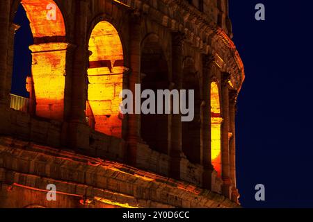 Magnificenza del Colosseo Romano di notte. Il Colosseo, illuminato di notte, mostra la sua grandezza contro un cielo scuro, mettendo in risalto il suo antico arco Foto Stock