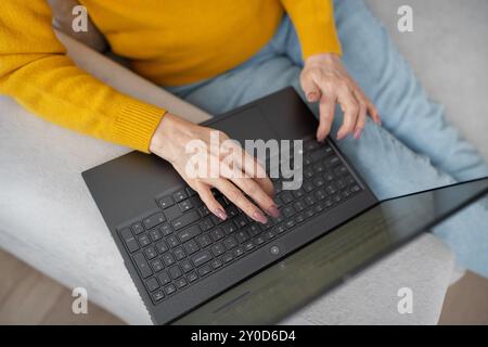 Una donna bionda lavora con molta attenzione dal suo ufficio domestico, scrivendo su un notebook Foto Stock