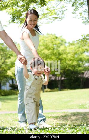 Ragazzo che cammina mano nella mano con i genitori Foto Stock