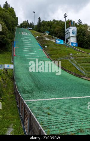 Un salto con gli sci nella Coppa del mondo di salto con gli sci nella città di Bischofshofen nelle Alpi austriache vicino a Salisburgo in una nuvolosa giornata estiva con cielo grigio. Foto Stock