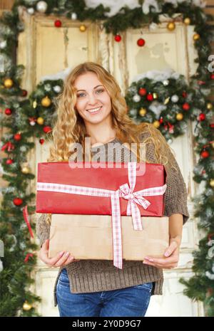 Felice giovane donna bionda azienda regali di Natale dalle decorazioni di Natale Foto Stock