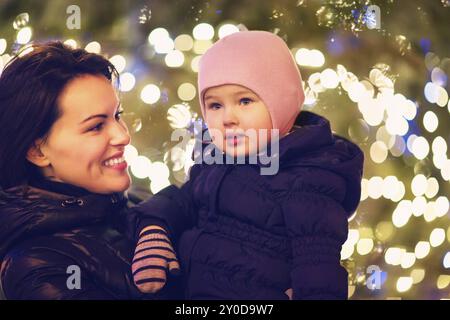 Madre e figlia piccola al di fuori su sfondo di Natale Foto Stock