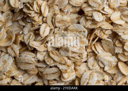 Versò una grande quantità di fiocchi di avena primo piano, sfondo di farina d'avena cruda cruda Foto Stock