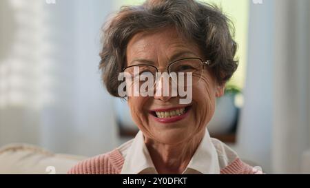 Caucasico pensivo bella nonna anziana donna guardando via allegro sorriso a macchina fotografica a casa vecchia donna matura anziana nonna in occhiali medici Foto Stock