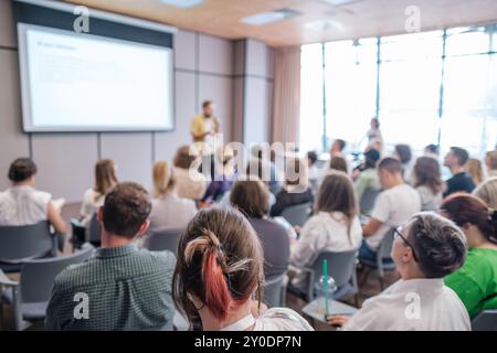 Gruppo di persone che partecipano a una presentazione in una sala conferenze. Relatore che tiene una lezione a un pubblico coinvolto. Foto Stock