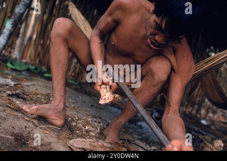 L'uomo indiano Yanomami forma un arco da caccia usando l'osso della mascella di un peccary. Nella foresta amazzonica nel Venezuela meridionale. Foto Stock