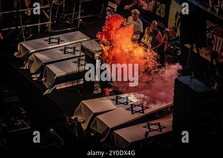 Tel Aviv, Israele. 1 settembre 2024. Liberata in ostaggio Ilana Gritzewsky, tiene una candela fumogena mentre si trova accanto a sei finte bare durante una protesta a Tel Aviv domenica, 1 settembre 2024. Gli organizzatori sostengono che oltre 700.000 israeliani sono saliti nelle strade delle città di tutto il paese domenica sera un giorno dopo che i corpi di Carmel Gat, Eden Yerushalmi, Hersh Goldberg-Polin, Alexander Lobanov, Almog Sarusi e il Maestro Ori Danino, sono stati salvati da Gaza. I manifestanti chiesero che il primo ministro Benjamin Netanyahu raggiungesse un accordo di cessate il fuoco con Hamas per riportare a casa i prigionieri rimasti. Foto di e Foto Stock