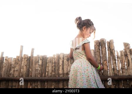 Giovane ragazza in un cortile illuminato dal sole, persa nel pensiero Foto Stock