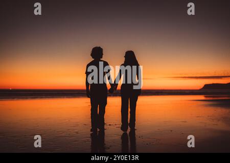 Sagoma di una coppia che si tiene per mano e si guarda l'un l'altro Foto Stock