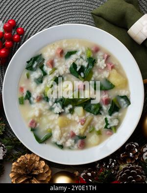 Zuppa di riso, prosciutto e spinaci, tapa spagnola tradizionale. Tavolo con vista dall'alto e decorazioni natalizie. Foto Stock