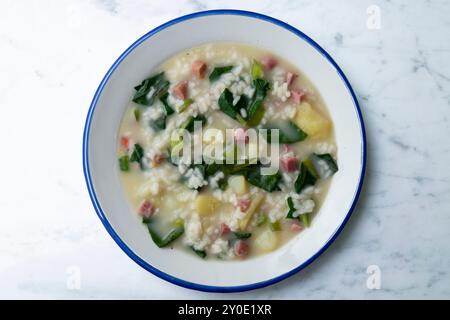 Zuppa di riso, prosciutto e spinaci, tapa spagnola tradizionale. Tavolo con vista dall'alto e decorazioni. Foto Stock