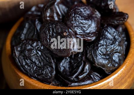 Pila nera di prugne mature, una pila di prugne su un tavolo di legno in cucina da vicino Foto Stock