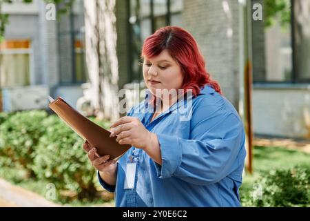 Una donna più grande con una camicia blu legge un documento all'aperto. Foto Stock