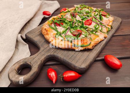 Pizza napoletana condita con verdure e acciughe su una tavola di legno, vista prospettica Foto Stock