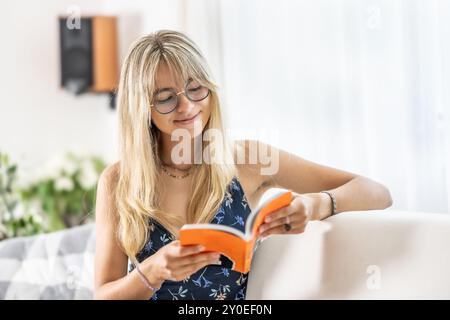 Una giovane signora sta leggendo un libro e indossa occhiali da vista. Foto Stock