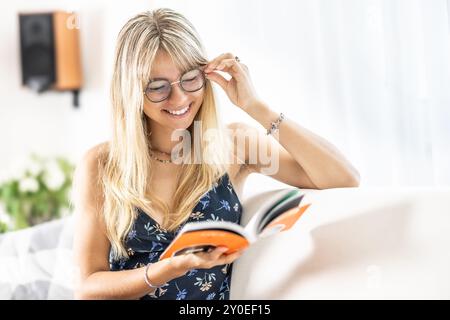 Una giovane signora sta leggendo un libro e indossa occhiali da vista. Foto Stock