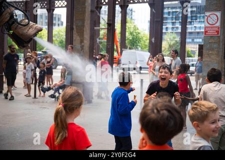 I bambini si divertono mentre vengono spruzzati dal tronco del grande Elefante a Nantes, Francia. Foto Stock