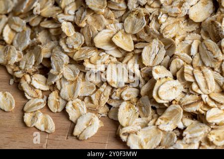 Versò una grande quantità di fiocchi di avena primo piano, sfondo di farina d'avena cruda cruda Foto Stock