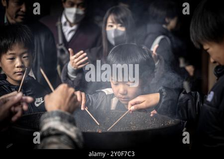 Famiglia giapponese che prega insieme a bastoni di incenso in un tempio in giappone Foto Stock