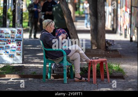 Tbilisi, Georgia - 8 ottobre 2023: Un venditore di souvenir siede all'ombra in un parco presso un mercato dell'artigianato di Tbilisi Foto Stock