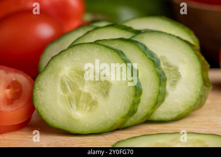 Cetriolo lungo verde a fette durante la preparazione dell'insalata, preparazione dell'insalata con verdure tagliate a pezzetti di cetrioli verdi Foto Stock