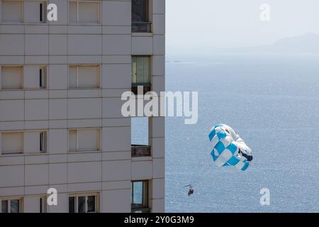 Foto di un Parasailer che sta navigando sull'oceano nella città di Benidorm, in Spagna, vicino a un condominio Foto Stock