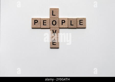 Primo piano di piastrelle di legno che formano un puzzle di parole incrociate con le parole "amore" e "persone": Concetto di affetto e comunità Foto Stock