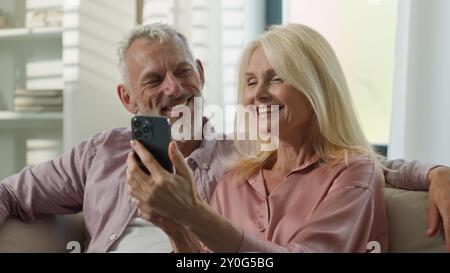 Famiglia felice senior 50s caucasica coppia anziana donna matura uomo donna donna donna maschio parlare video chiamata Internet sorriso nonni utilizzare il telefono cellulare Foto Stock