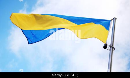 Ondeggiando la bandiera nazionale Ucraina ondeggia su Una pala Flagpole sullo sfondo del cielo Foto Stock
