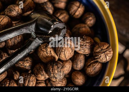 Noci e schiaccianoci nel primo piano del recipiente. Deliziose noci per una dieta vegetariana Foto Stock