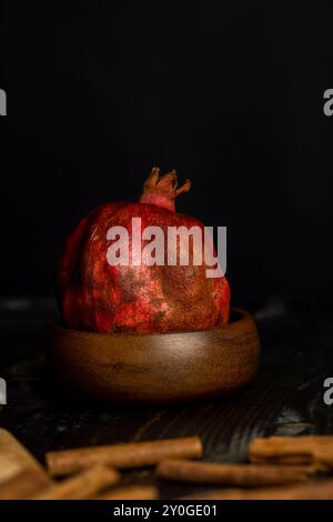 Un piccolo melograno rosso maturo è sdraiato sul tavolo, un frutto di melograno rosso maturo con grossi chicchi dolci Foto Stock