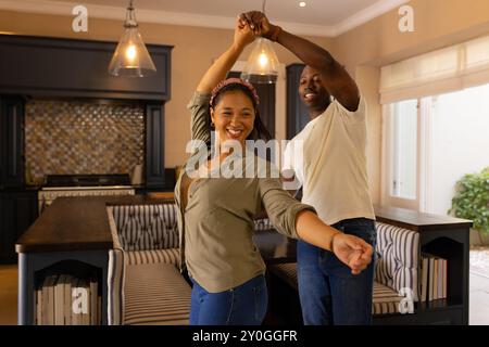 Ballare insieme in cucina, coppie multirazziali che si godono momenti di qualità a casa Foto Stock