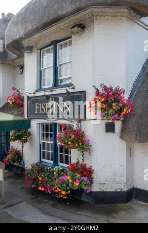 The Fish Inn, un attraente pub sul fiume a Ringwood, Hampshire, Inghilterra, Regno Unito, con fiori colorati in cesti appesi Foto Stock