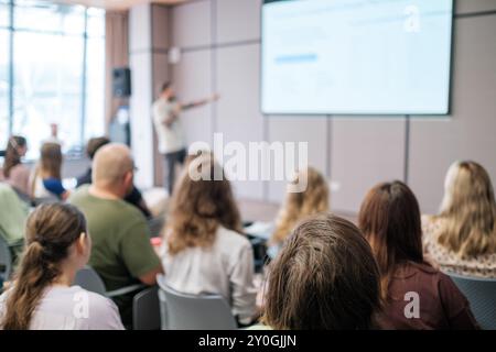 Immagine sfocata della presentazione aziendale con il pubblico seduto in una moderna sala conferenze, concentrandosi sull'apprendimento e la collaborazione Foto Stock