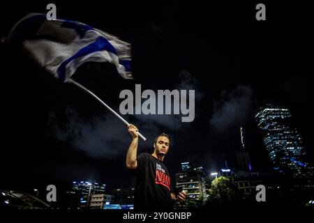 Tel Aviv, Israele. 1 settembre 2024. Un manifestante ondeggia la bandiera israeliana durante la manifestazione. Gli organizzatori sostengono che oltre 700.000 israeliani sono saliti nelle strade delle città di tutto il paese domenica sera un giorno dopo che i corpi di Carmel Gat, Eden Yerushalmi, Hersh Goldberg-Polin, Alexander Lobanov, Almog Sarusi e il Maestro Ori Danino, sono stati salvati da Gaza. I manifestanti chiesero che il primo ministro Benjamin Netanyahu raggiungesse un accordo di cessate il fuoco con Hamas per riportare a casa i prigionieri rimasti. (Foto di Eyal Warshavsky/SOPA Images/Sipa USA) credito: SIPA USA/Alamy Live News Foto Stock