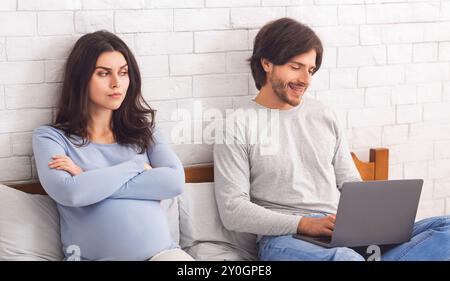 Una donna incinta ha offeso il marito che giocava al computer portatile Foto Stock