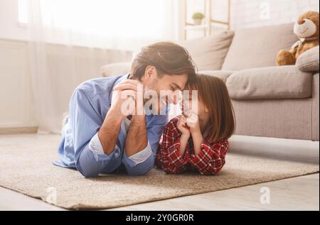 Bel papà e la sua ragazza liitle che si stesa sul pavimento Foto Stock