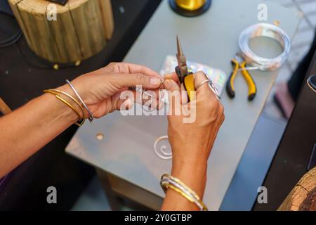 Donna ispanica irriconoscibile che realizza orecchini negli anni '50 sul suo stallo di strada e vende gioielli in filo di alluminio fatti a mano Foto Stock