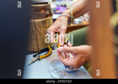 Donna ispanica irriconoscibile che realizza orecchini negli anni '50 sul suo stallo di strada e vende gioielli in filo di alluminio fatti a mano Foto Stock