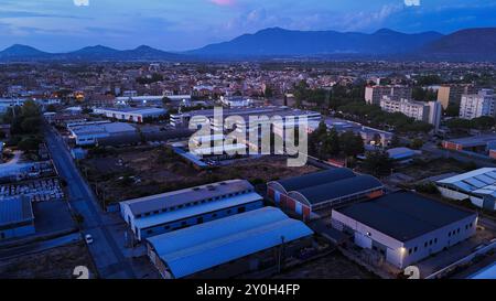 Zona industriale con fabbriche e magazzini al crepuscolo nella periferia Foto Stock