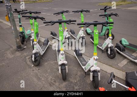 Gruppo di scooter elettrici Lime parcheggiato sul marciapiede a Berlino, Germania Foto Stock