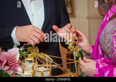 Gli sposi si scambiano anelli, lo sposo mette l'anello sulla mano della sposa nell'ufficio del registro dei matrimoni. Le spose indossano un anello sulla mano della sposa. ING Foto Stock